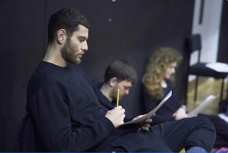 Course Fees for Drama Schools in the UK. Two young males and one female sitting and reading a script
